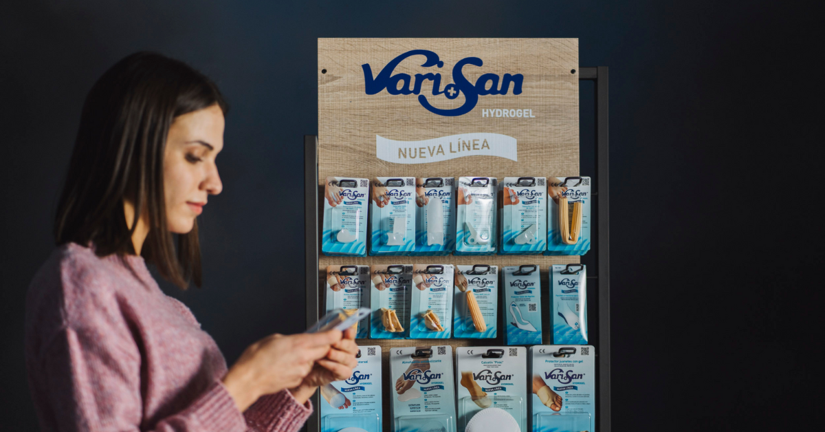 Persona consultando productos de cuidado del pie en un expositor de farmacia, imagen utilizada por Farmavari en contenidos de salud podológica